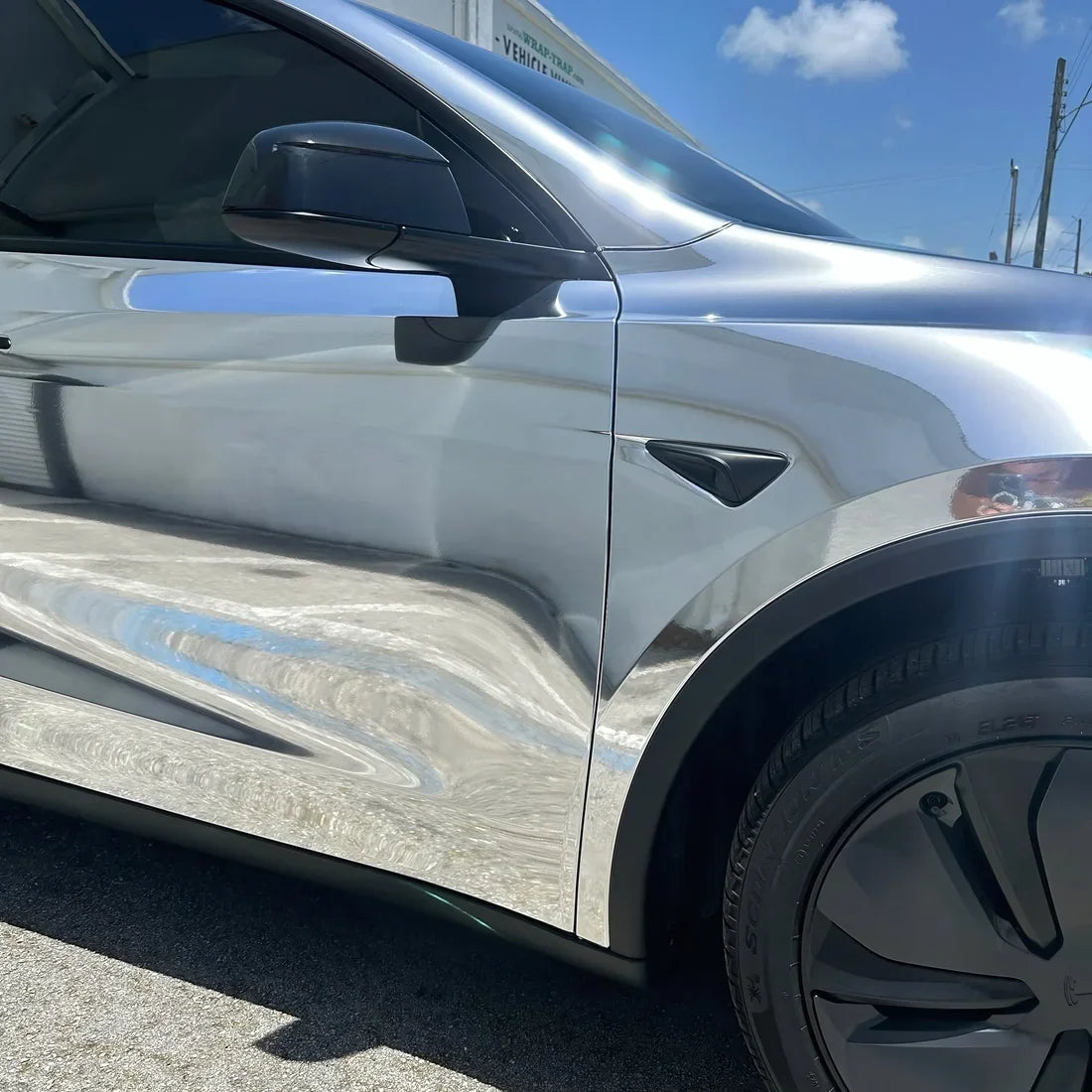 Chrome White Gold Vinyl Wrap Tesla reflecting light across its sleek.