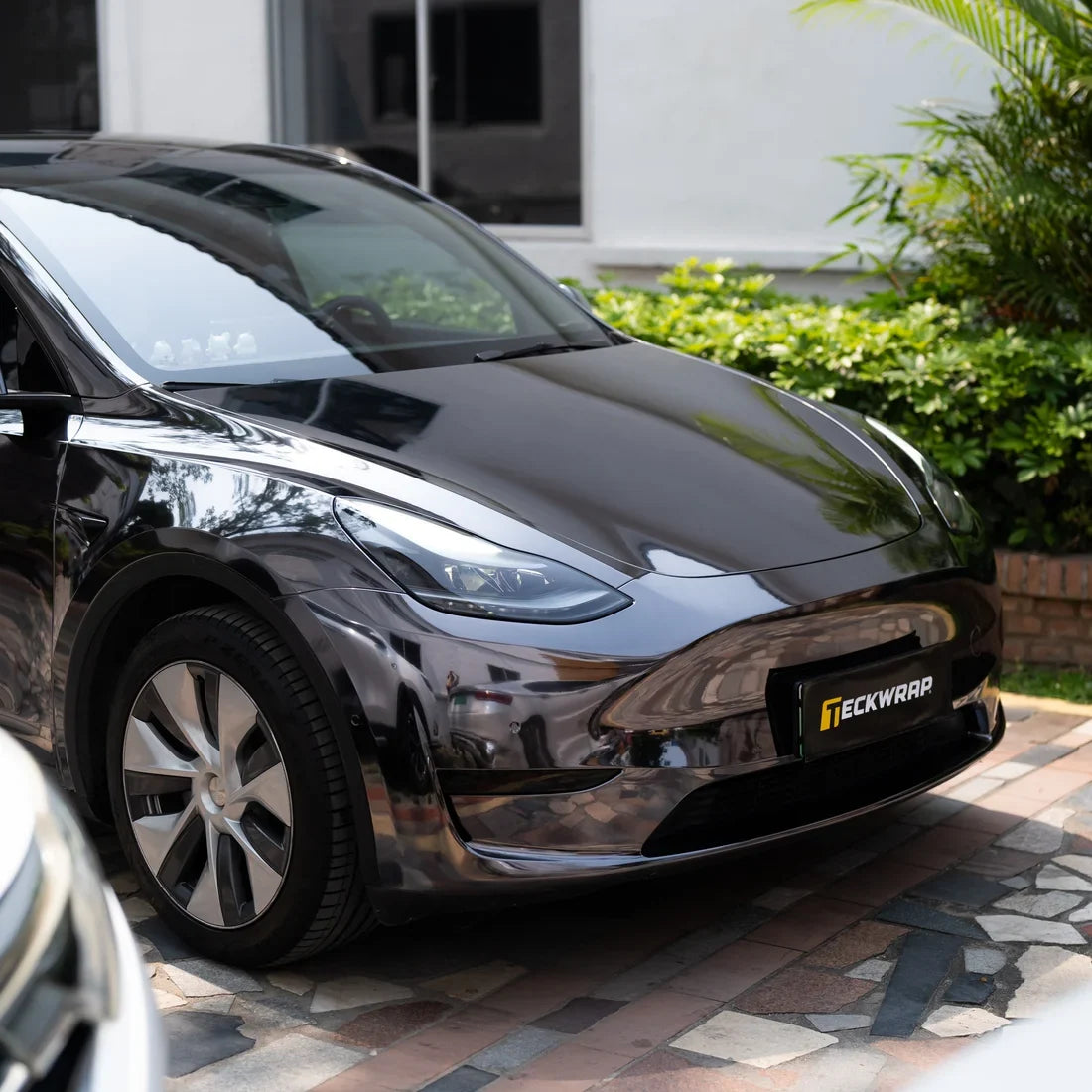 Black Tesla displaying a smooth Jet Black Mirror Chrome vinyl wrap finish.