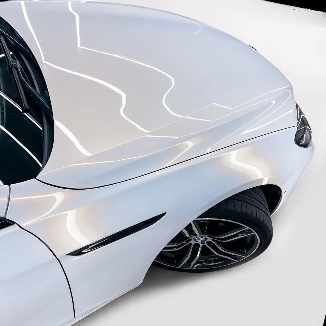 Close-up of a glossy gold pearl white chameleon car wrap on body
