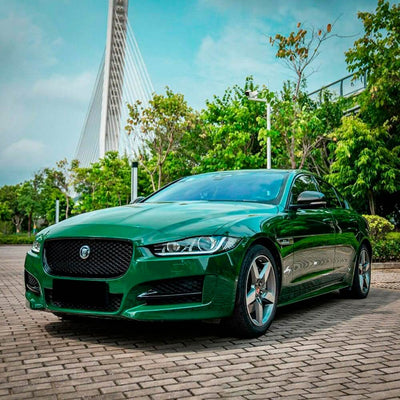 A Jaguar XE sedan customized with a vibrant high-gloss green vinyl wrap